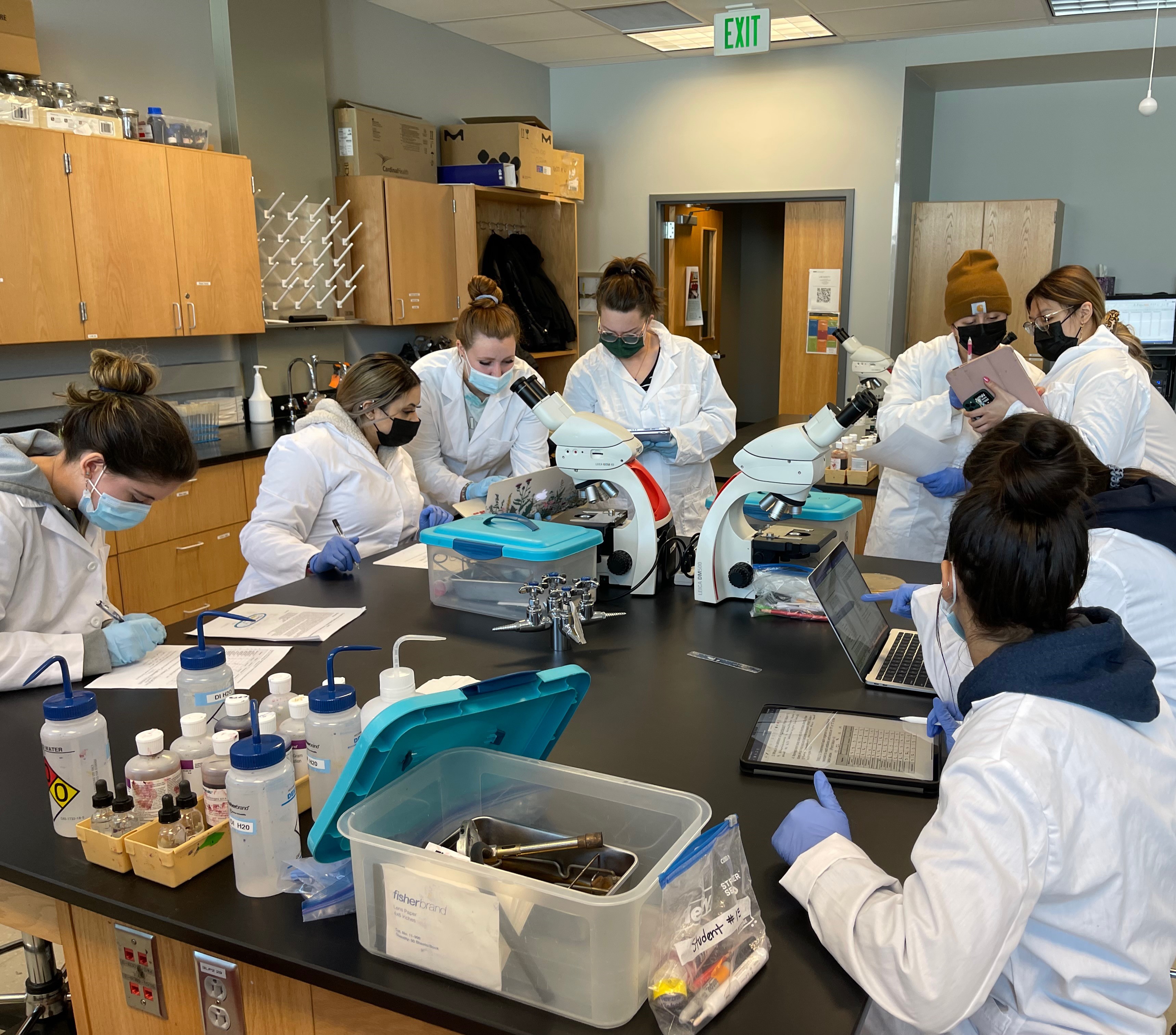 students in lab coats using equipment